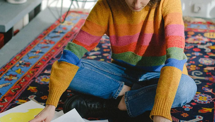 A young person in a rainbow jumper doing expressive art therapy